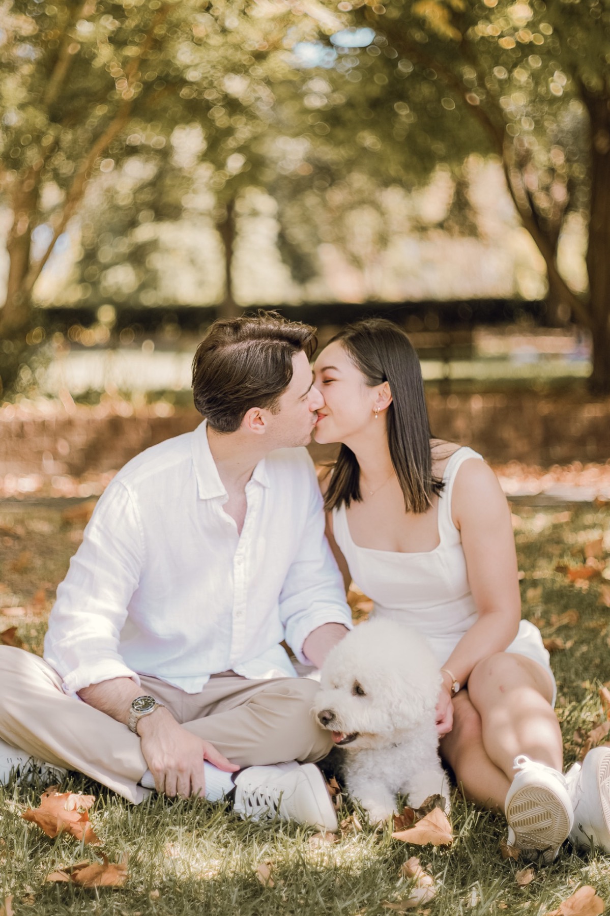 Damon and Christina kissing on the grass with Marlo sitting between them