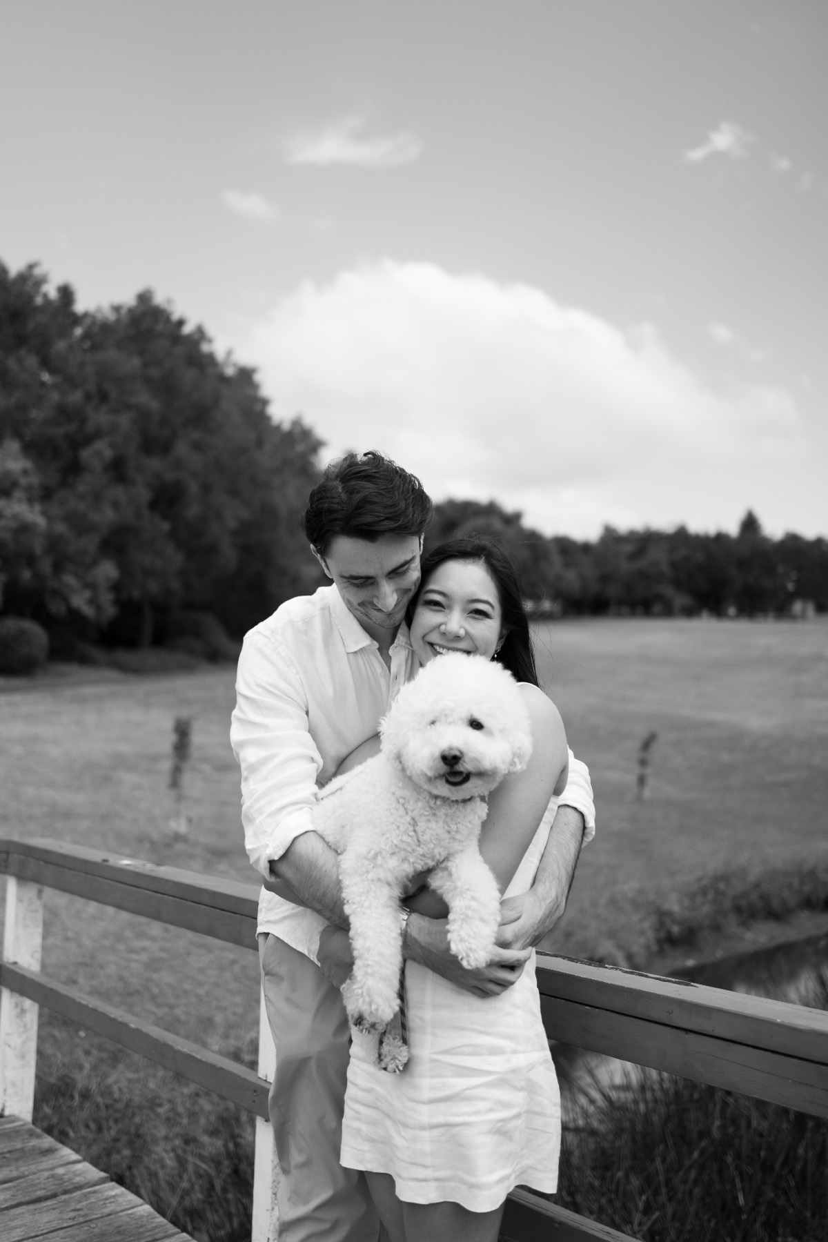 Black and white photo of Damon holding Christina and Marlo on a wooden bridge