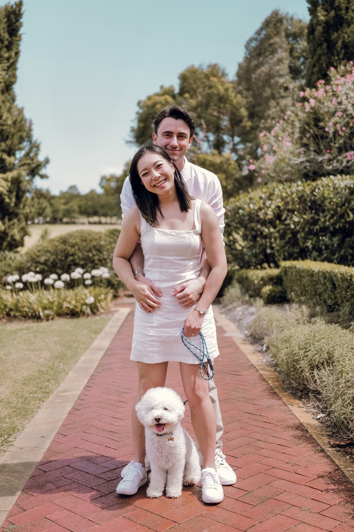 The couple standing on a brick garden path with Marlo on a lead in front
