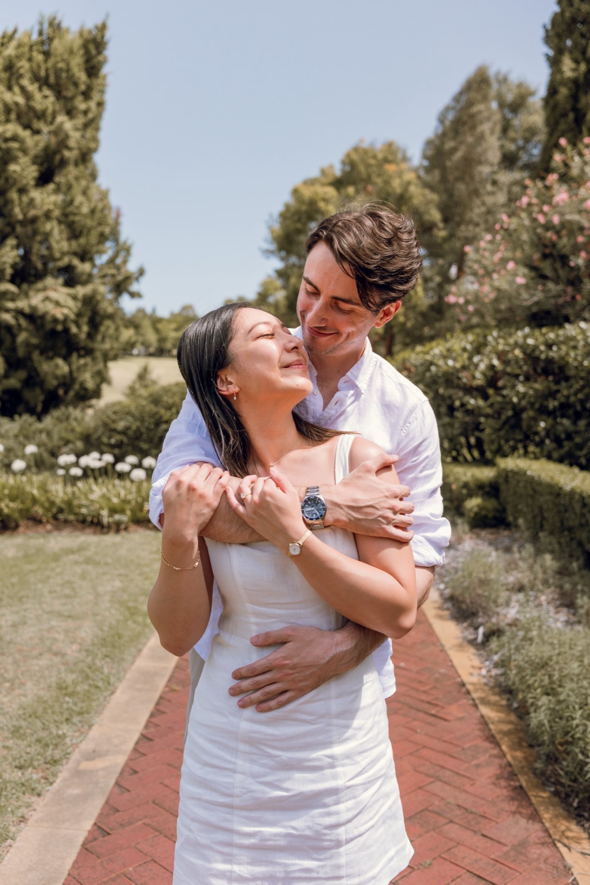 Christina laughing up at Damon as he wraps his arms around her in the garden