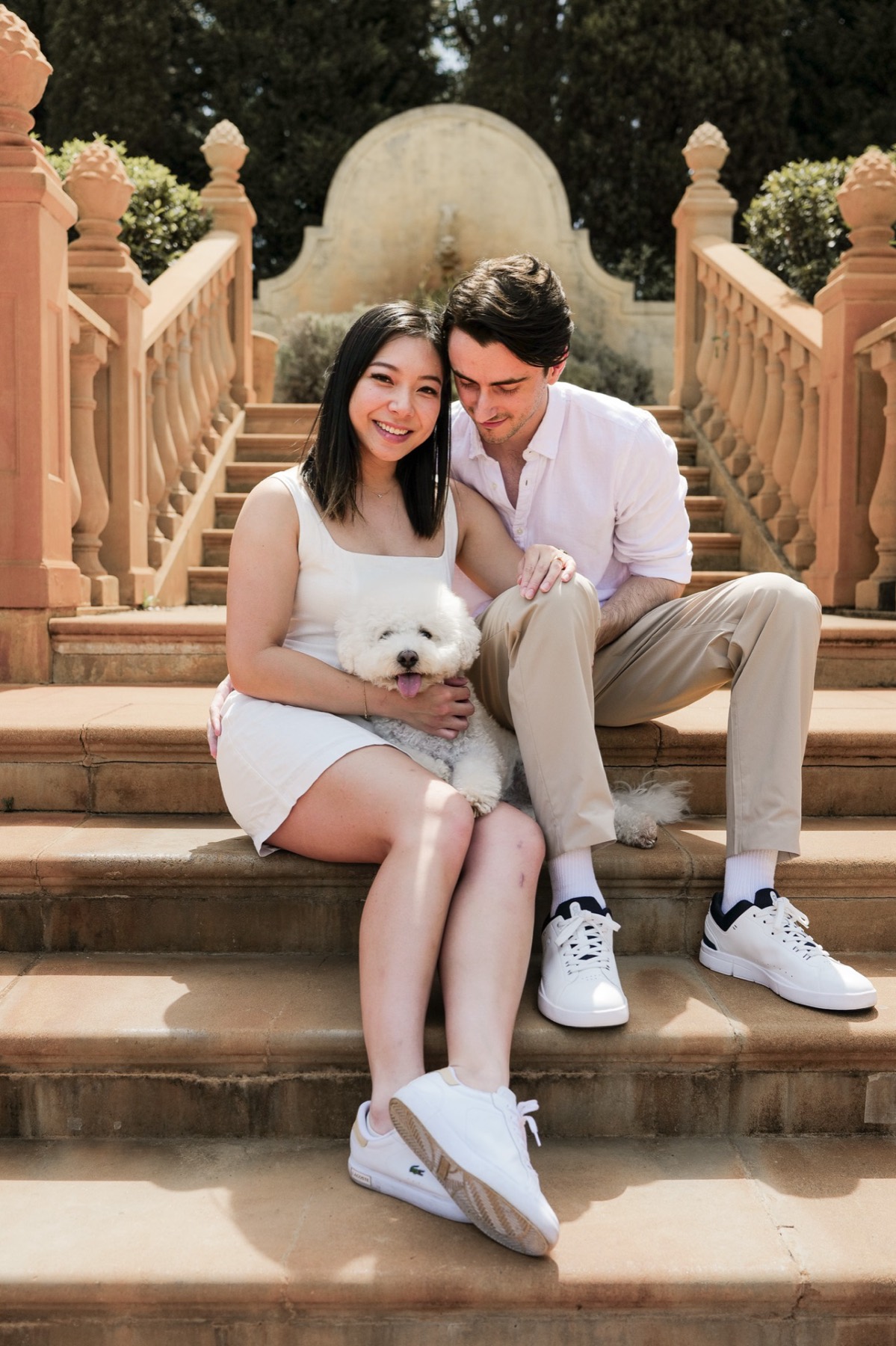 The couple sitting on sandstone garden steps with Marlo on Christina's lap
