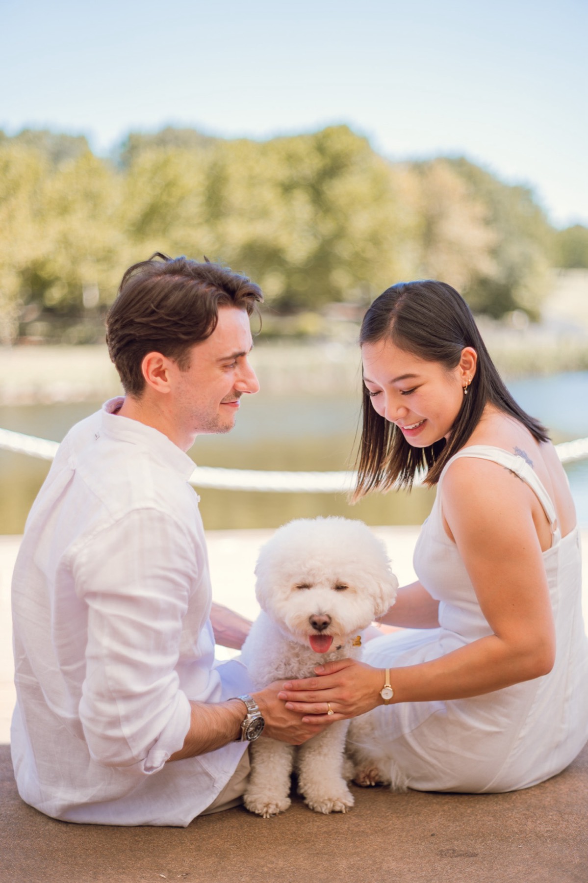 The couple sitting by the lake smiling down at Marlo between them