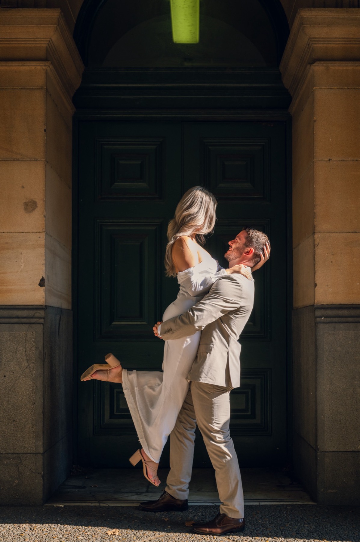 Dave lifting Kim off the ground in front of a heavy dark door