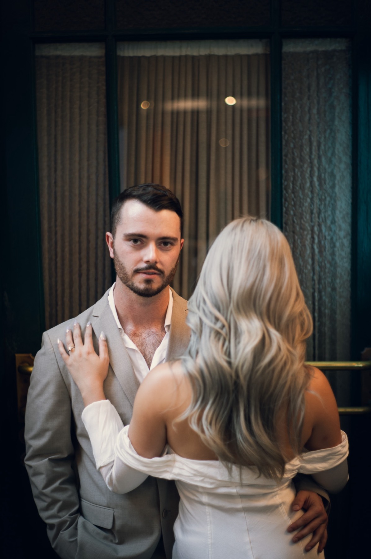 Dave gazing towards the camera as Kim, seen from behind, rests her hand on his shoulder