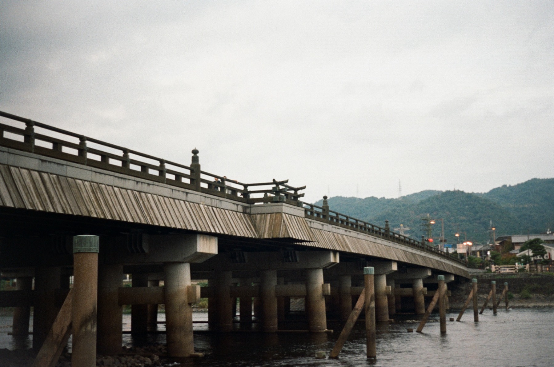 A long traditional wooden bridge stretching across a grey river