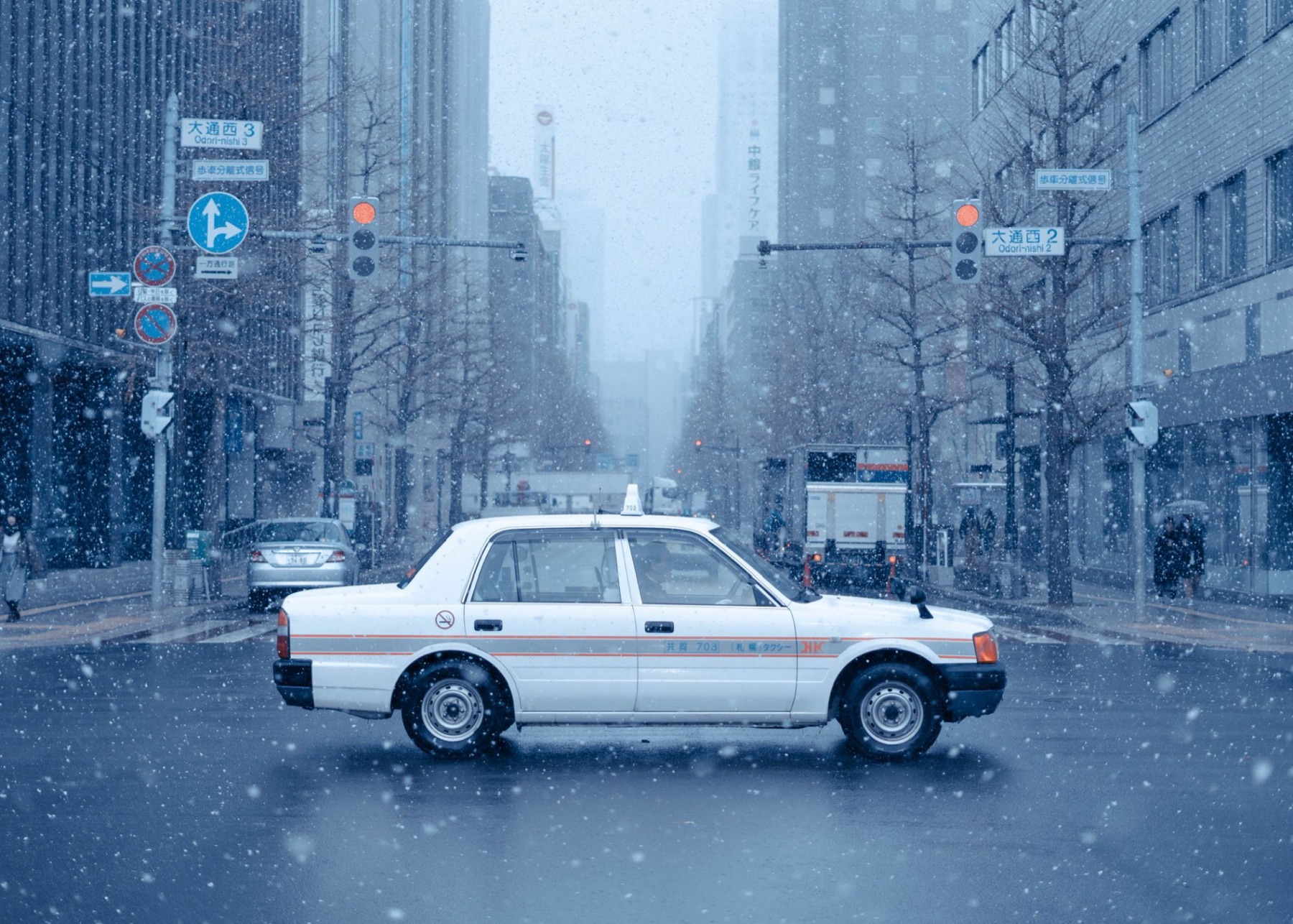 A white taxi crossing a snowy Sapporo intersection on Odori