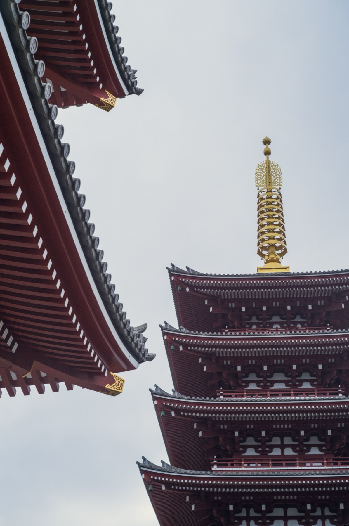 Senso-ji's five-storey pagoda and its golden spire beside a sweeping temple roof