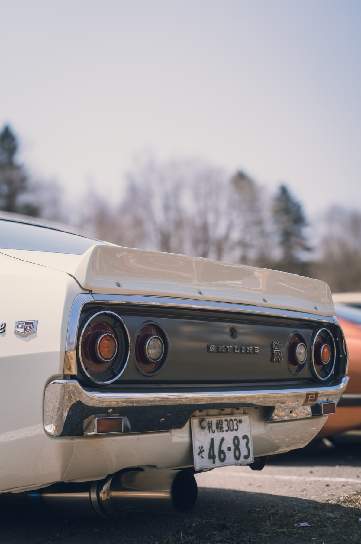 The chrome tail and round lamps of a classic white Nissan Skyline GT-R on a Sapporo street