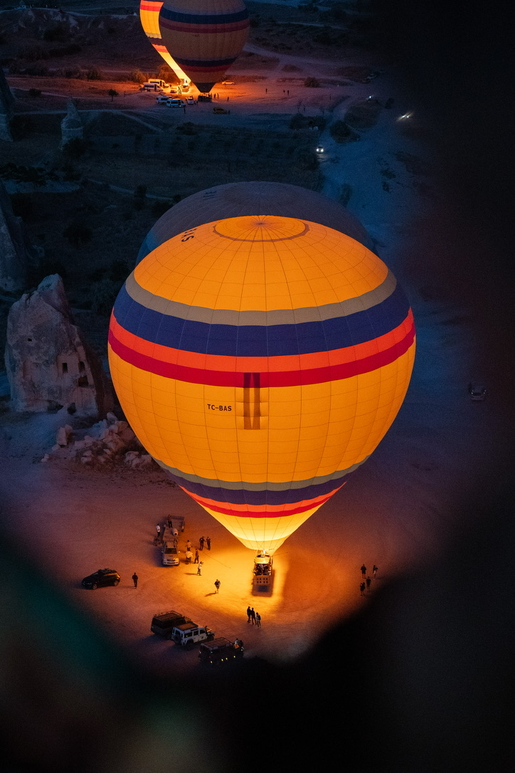 A hot air balloon glowing before dawn, seen from above through the edge of a basket