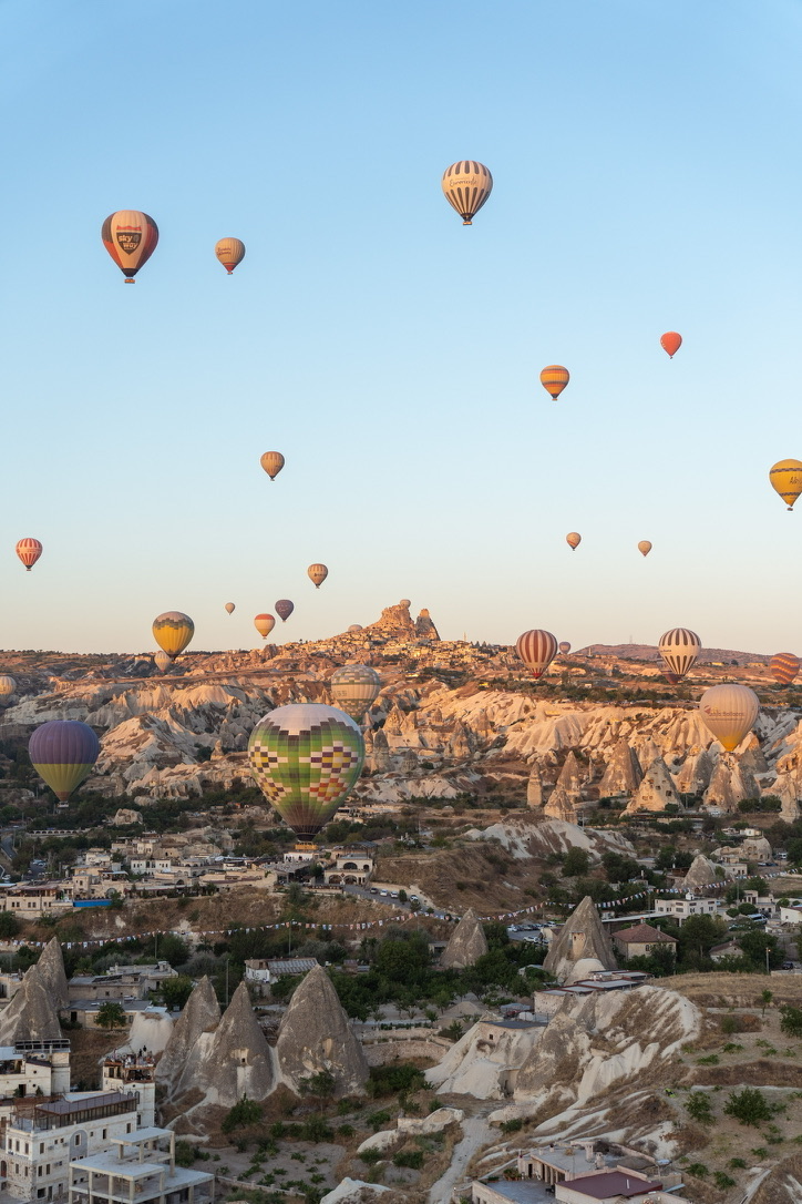 Dozens of balloons drifting over Cappadocia's fairy chimneys at sunrise