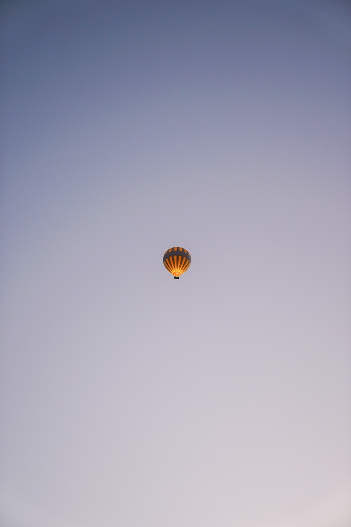 A lone glowing balloon in a pale lavender dawn sky