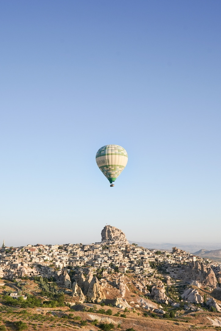 A single balloon above Uçhisar Castle and the cave town below