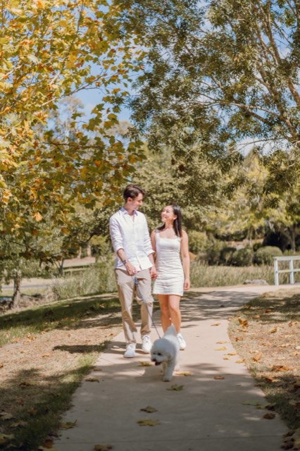 Damon and Christina walking Marlo along a leafy park path