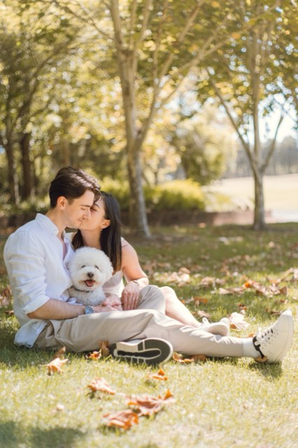 The couple kissing on the grass under the trees with Marlo in Damon's lap