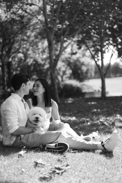 Black and white photo of the couple sitting on the grass nose to nose, Marlo in Damon's lap