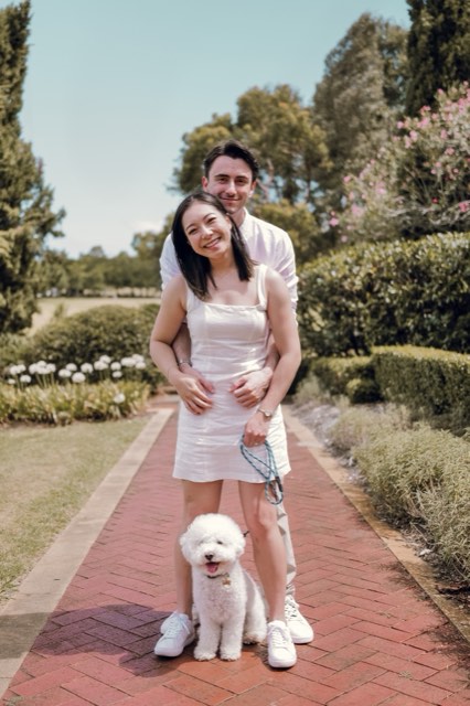 The couple standing on a brick garden path with Marlo on a lead in front