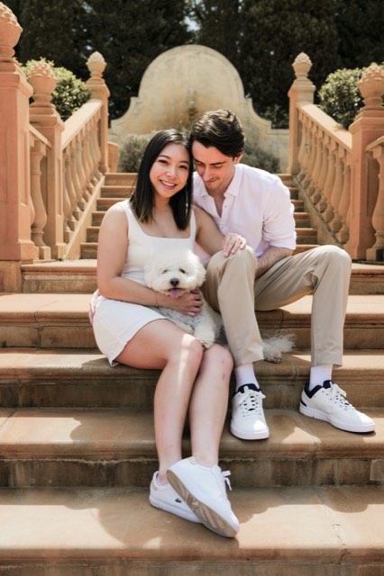 The couple sitting on sandstone garden steps with Marlo on Christina's lap