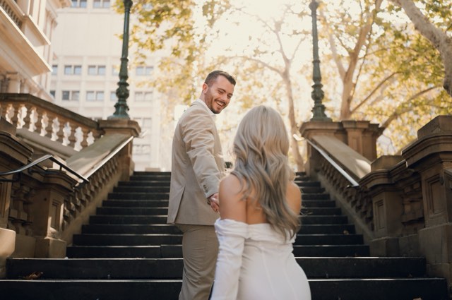 Dave and Kim climbing a sandstone staircase in the city, Dave looking back over his shoulder with a smile