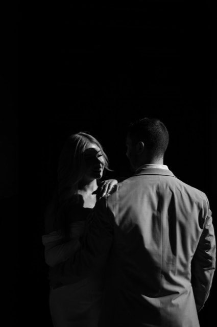 Black and white portrait of the couple in deep shadow, Kim's face lit by a thin strip of light