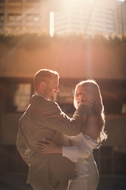 Kim laughing with her arms around Dave, both glowing in low golden backlight